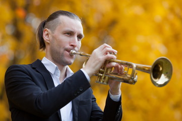 musician playing trumpet in park 