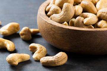 roasted salted raw cashew nuts in wooden bowl on rustic table, healthy vegetarian snack, Anacardium occidentale