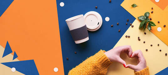 Zero waste coffee concept. Eco friendly reusable coffee cups in hands. Panoramic geometric flat lay on split paper background. Creative flat layout in classic blue, orange and yellow colors.