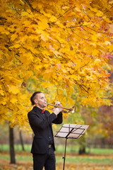 young trumpeter blowing his trumpet near music stand with notes autumn nature 