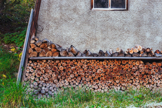 Logs stacked in a woodpile near wall