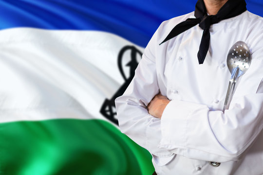 Lesotho domestic food concept. Professional chef in white uniform is standing with metal spatula. Copy space for text.