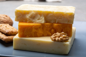 Cheese collection, matured and orange original British cheddar cheese in blocks served on grey plate