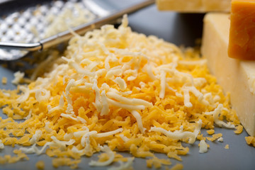 Cheese collection, matured and orange original British cheddar cheese in blocks and grated served on grey plate