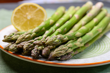 Bunch of fresh green raw organic asparagus with lemon ready to cook