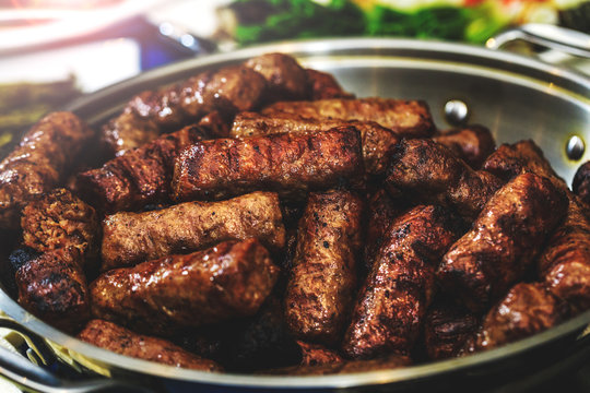 Sausages in bowl, grilled and cooked for the holiday table. Homemade barbecue grill in rustic pan. Delicious Romanian mici or mititei as traditional food. Close up picture with tasty bbq.