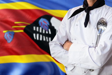 Swaziland domestic food concept. Professional chef in white uniform is standing with metal spatula. Copy space for text.