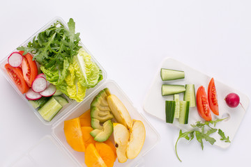 lunch box with a vegetarian set of fresh vegetables and fruits for a quick lunch on a white background Top view