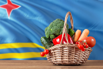 Aruba organic food concept. National flag background with basket full of vegetables on wooden table. Copy space for text.