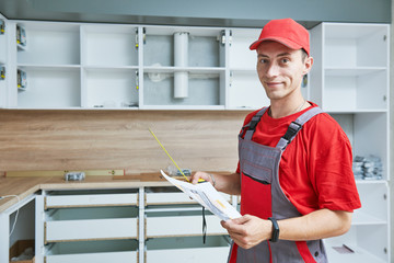 kitchen installation. Worker assembling furniture