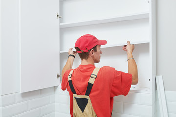 cabinet shelf installation. Worker assembling furniture