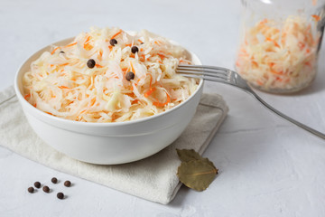 Homemade sauerkraut. Fermented food. Sauerkraut with carrots in a white bowl on a white background close up.