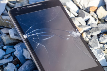 Frustrated phone on the rocks. Glass shattered on rocks on a sma