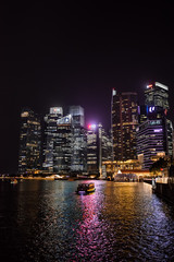 Fototapeta na wymiar Singapore skyline and river at night with a boat.