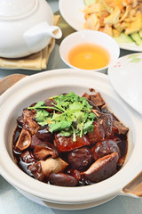 Delicious braised pigs feet in brown sauce in white pot