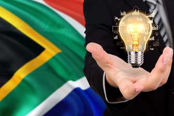 South Africa creativity concept. Businessman with a light bulb in his hand on national background....