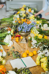 on a wooden table are hyacinths, roses, peonies, daffodils, anemones, and other flowers. Education. Florist communication with customer in the workshop in the studio with flowers.