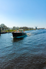 Waterways of North Holland with boats and view on traditional Dutch mill, spring landscape