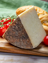 Italian cheese, piece of mature Tuscan Pecorino sheep cheese served with olive bread and tomatoes