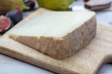 Piece of French cheese Tomme de Brebis made from sheep milk served as dessert with fresh figs and pears