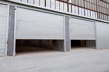 gray iron shutter of an industrial building with gray concrete porch, side view nobody.