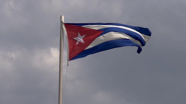 Close up of a Cuban Flag waving in the wind, slow motion footage with a dramatic sky in the background.