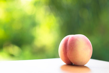 An attractive peach is placed on a wooden board with a faded yellow-green background.