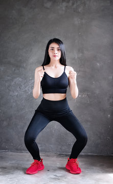 The beautiful woman wearing black exercise suit ,raise fists up beside her body and kneel down,doing exercise at home