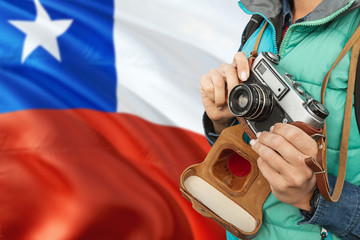Chile photographer concept. Close-up adult woman holding retro camera on national flag background. Adventure and traveler theme.