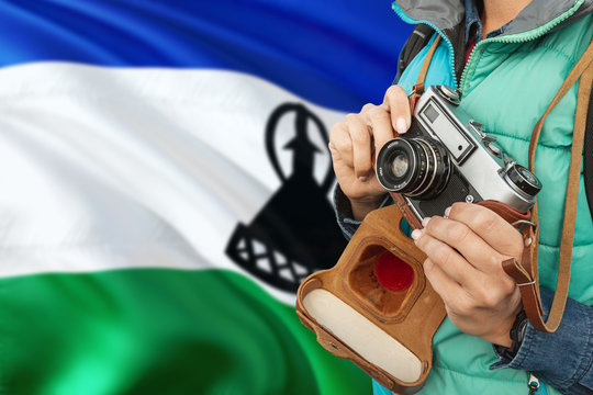 Lesotho photographer concept. Close-up adult woman holding retro camera on national flag background. Adventure and traveler theme.