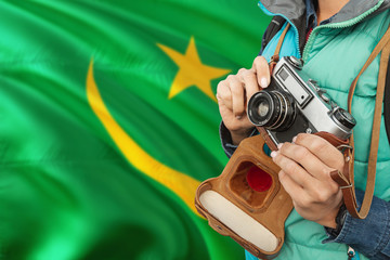 Mauritania photographer concept. Close-up adult woman holding retro camera on national flag background. Adventure and traveler theme.