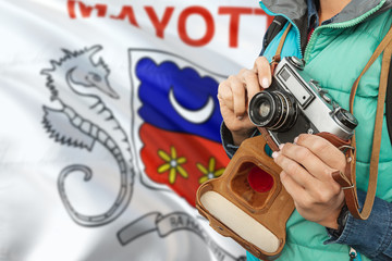 Mayotte photographer concept. Close-up adult woman holding retro camera on national flag background. Adventure and traveler theme.