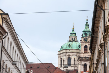 Fototapeta na wymiar St Nicholas Church, also called Kostel Svateho Mikulase, in Prague, Czech Republic, with its iconic dome seen from nearby streets with typical baroque facade. It's one of main landmarks