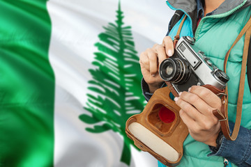 Norfolk Island photographer concept. Close-up adult woman holding retro camera on national flag background. Adventure and traveler theme.