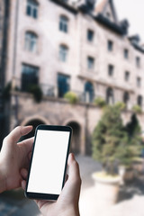 close up of man hands with smartphone texting message on city street blurred background. blank screen for graphics display montage.