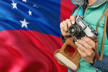 Samoa photographer concept. Close-up adult woman holding retro camera on national flag background....
