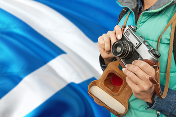 Scotland photographer concept. Close-up adult woman holding retro camera on national flag background. Adventure and traveler theme.