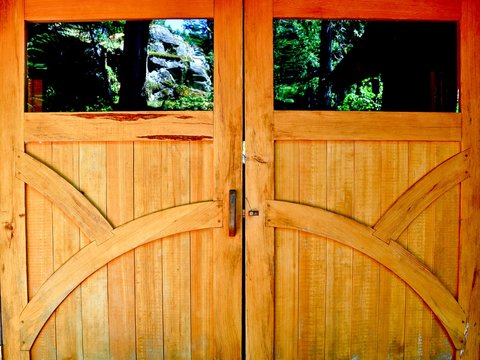Wooden doors showcasing craftsmanship with windows reflecting the forest 