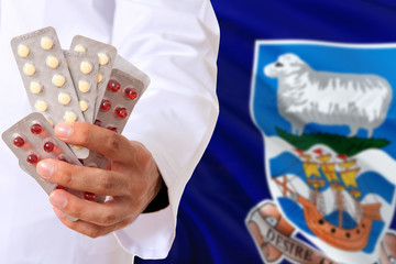 Falkland Islands pharmacy and medicine concept. Doctor holding pills tablet on national flag background. Health theme with copy space for text.