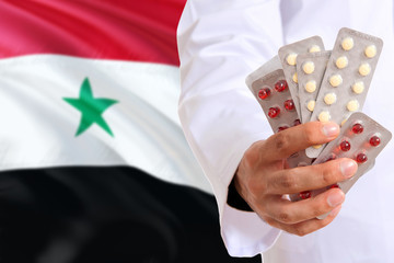 Syria pharmacy and medicine concept. Doctor holding pills tablet on national flag background....