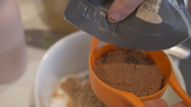 Powdered Cocoa being measured and poured while making vegan brownies