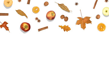 Autumn background. Border  made of apples, dried orange, fall leaves, cinnamon, nuts and anise on white. Flat lay composition with fruits and spices.