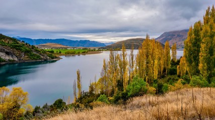 Fototapeta na wymiar A panoramic view of a beautiful freshwater lake in autumn, surrounded by rolling hills and rural farmland, on the South Island of New Zealand.