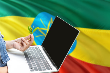 Ethiopia modern agriculture concept. Farmers holding laptop, check tea on national flag background. Ecology theme with copy space.