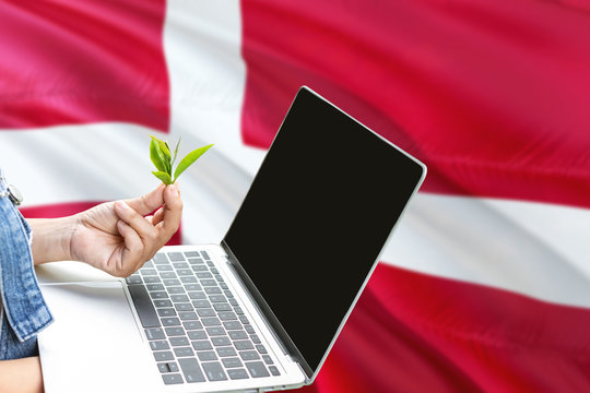 Denmark modern agriculture concept. Farmers holding laptop, check tea on national flag background. Ecology theme with copy space.