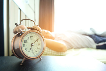 Morning of a new day, alarm clock wake up man sitting in the room. A man stretch the muscles at...
