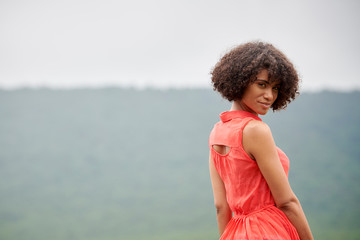 Gorgeous biracial young woman poses looking back over her shoulder in red dress - Powered by Adobe