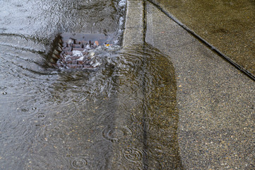 Heavy rain caused flooding in street, water swirling around storm drain