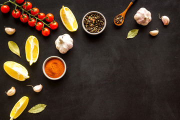 Cooking background with spices and vegetables. pepper, garlic, cherry tomatoes on black desk top-down frame copy space