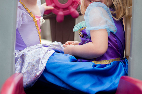 young girls in princesss dresses play together on toy